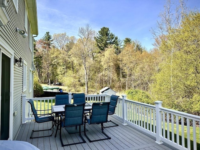 wooden deck featuring outdoor dining area and a view of trees