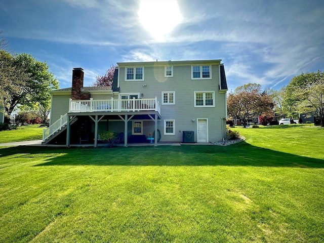 back of property featuring a wooden deck, a lawn, stairway, and a chimney