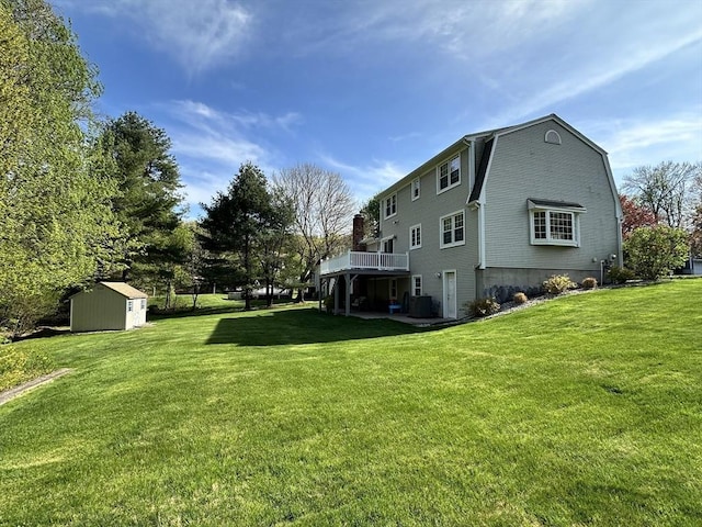 back of property with a storage shed, an outbuilding, a yard, and a deck