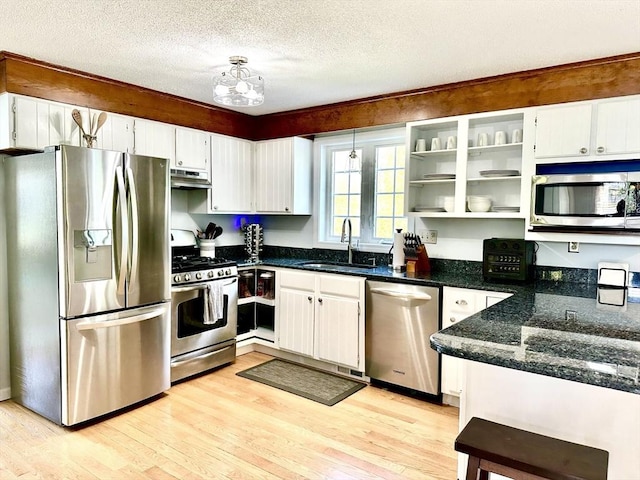 kitchen with stainless steel appliances, a sink, light wood-style floors, a textured ceiling, and white cabinetry