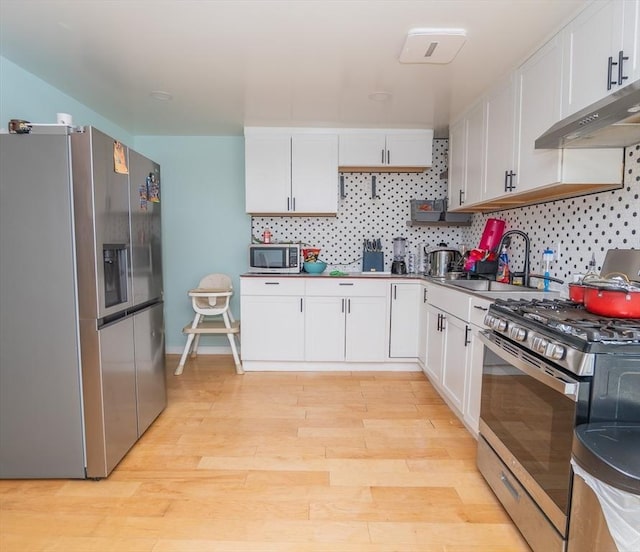 33 Williams St, New London, CT 06320 - kitchen with stainless steel appliances, under cabinet range hood, white cabinets, light wood-type flooring, and backsplash