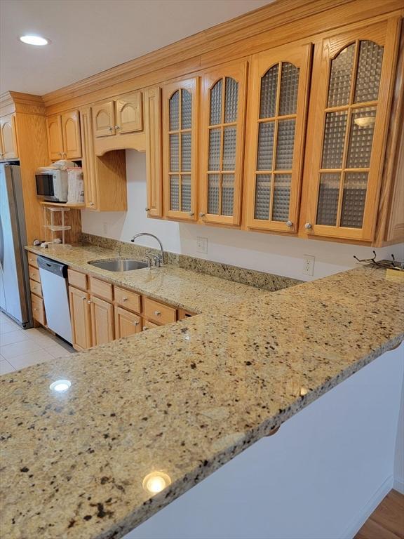 281 Rowley Bridge Rd Unit 7, Topsfield, MA 01983 - kitchen featuring dishwashing machine, freestanding refrigerator, light stone countertops, white microwave, and glass insert cabinets
