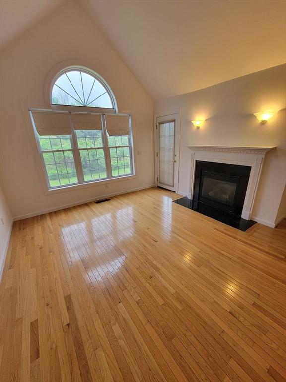 281 Rowley Bridge Rd Unit 7, Topsfield, MA 01983 - unfurnished living room with light wood-style floors, lofted ceiling, a fireplace with flush hearth, and baseboards