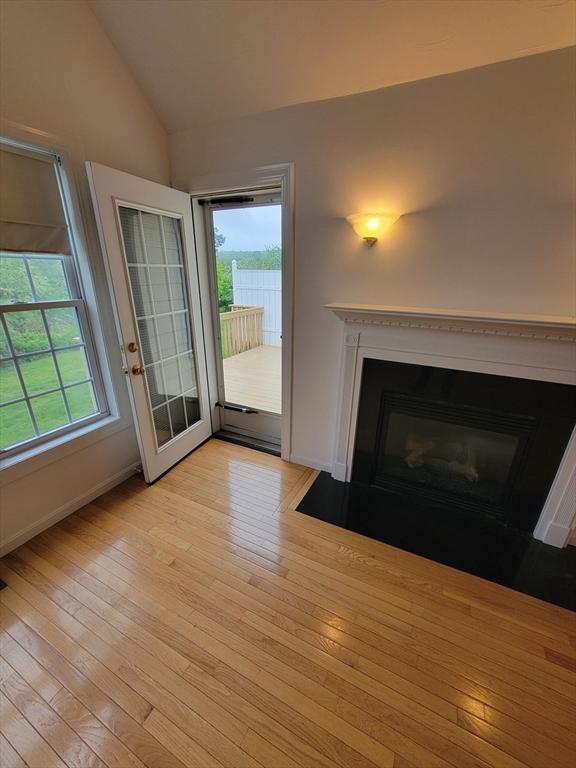 281 Rowley Bridge Rd Unit 7, Topsfield, MA 01983 - unfurnished living room featuring a fireplace with flush hearth, light wood-style flooring, lofted ceiling, healthy amount of natural light, and baseboards