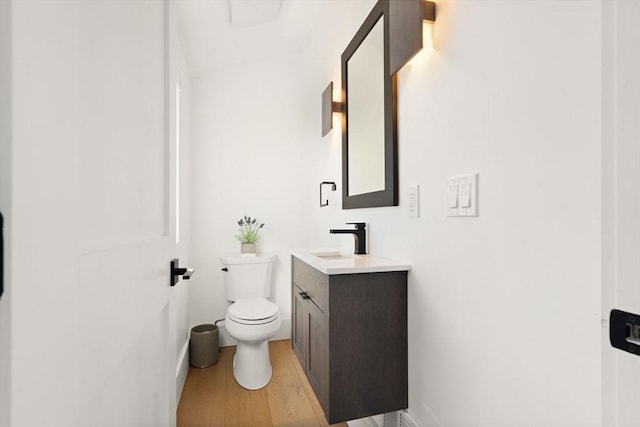 half bathroom with vanity, toilet, and wood finished floors