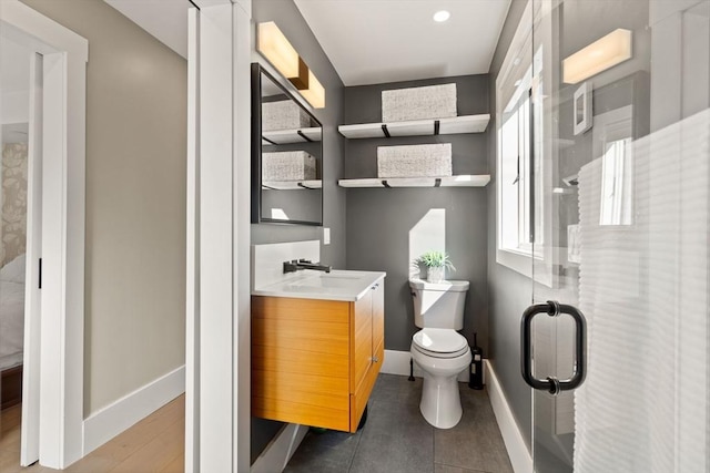 full bath featuring a stall shower, baseboards, vanity, and toilet