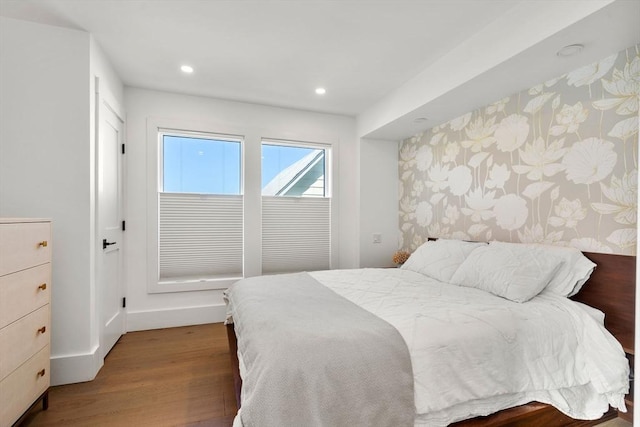 bedroom with recessed lighting, an accent wall, wood finished floors, baseboards, and wallpapered walls