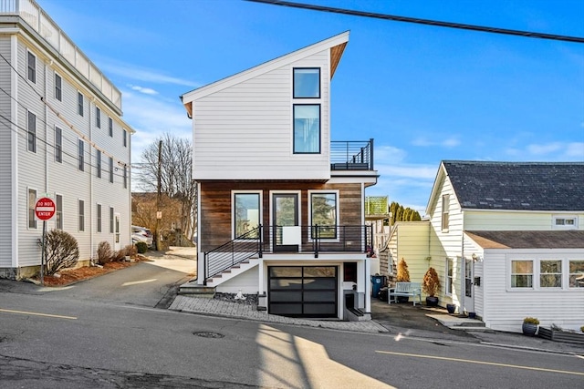 view of front of property featuring stairway, an attached garage, and a balcony