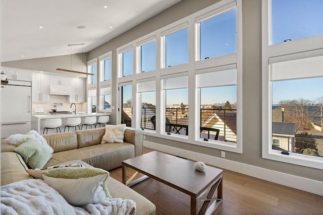 living area with light wood-type flooring, baseboards, a high ceiling, and recessed lighting