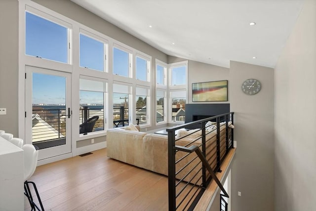 living room featuring high vaulted ceiling, a wealth of natural light, visible vents, and wood finished floors