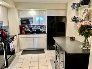 40 Village Rd Unit 606, Middleton, MA 01949 - kitchen with black appliances, dark countertops, white cabinets, and light tile patterned floors