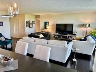 40 Village Rd Unit 606, Middleton, MA 01949 - living room featuring a textured ceiling, a chandelier, and wood finished floors