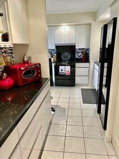 40 Village Rd Unit 606, Middleton, MA 01949 - kitchen featuring decorative backsplash, dark countertops, and light tile patterned flooring