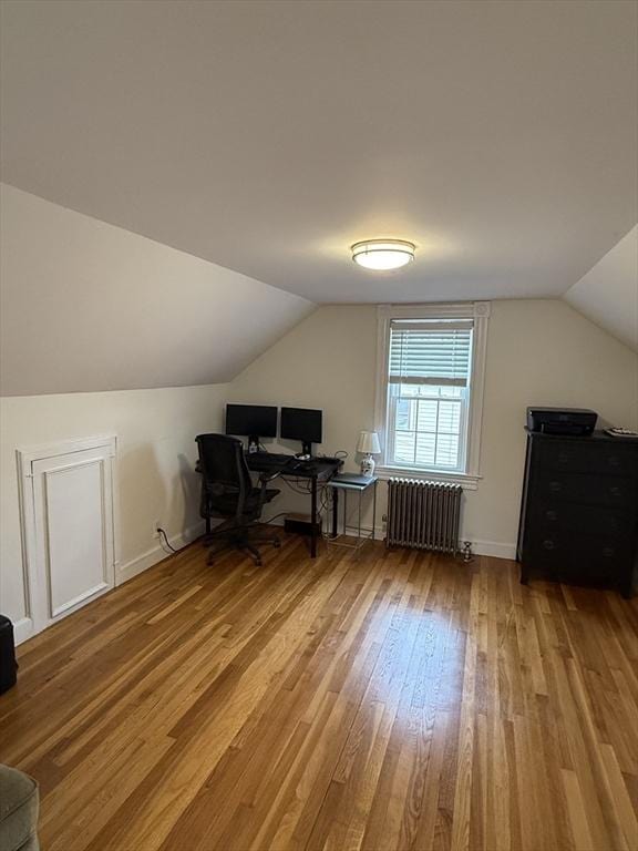 office area featuring hardwood / wood-style flooring, lofted ceiling, and radiator