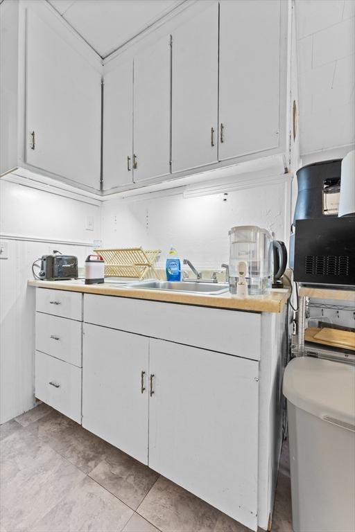 kitchen with white cabinetry, light tile patterned flooring, and sink