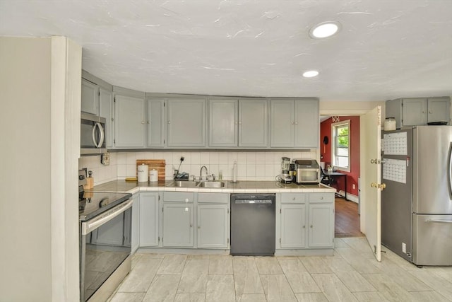 120 E Ashland St, Brockton, MA 02302 - kitchen featuring stainless steel appliances, a sink, tile counters, gray cabinets, and backsplash
