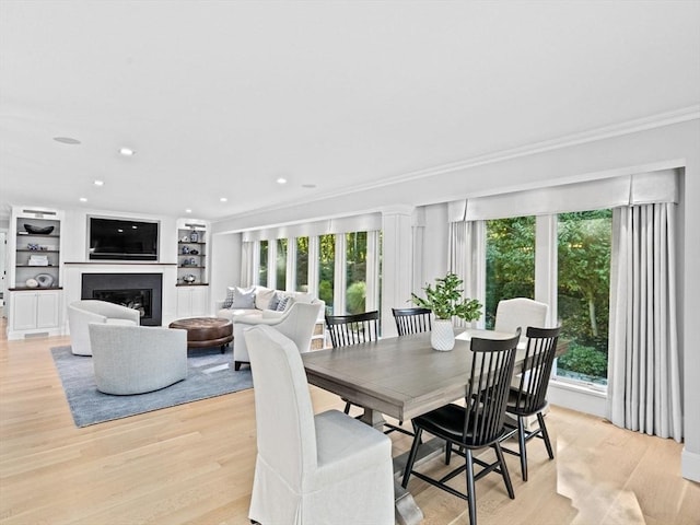 1164 Main St, Hingham, MA 02043 - dining area with crown molding, light wood-type flooring, a glass covered fireplace, recessed lighting, and built in features