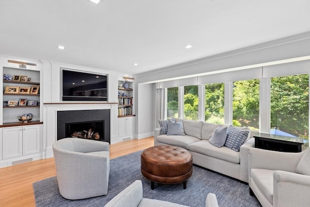 1164 Main St, Hingham, MA 02043 - living room featuring light wood finished floors, a fireplace, crown molding, built in shelves, and recessed lighting