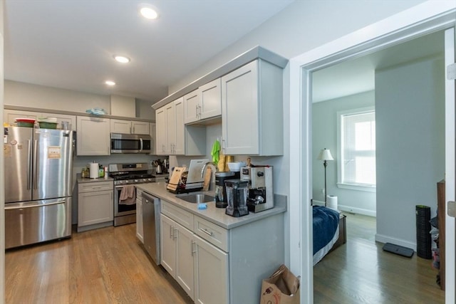 kitchen with stainless steel appliances, a sink, light wood-style flooring, light countertops, and recessed lighting