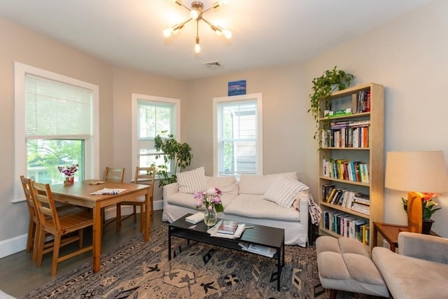 living area with baseboards, wood finished floors, and a chandelier