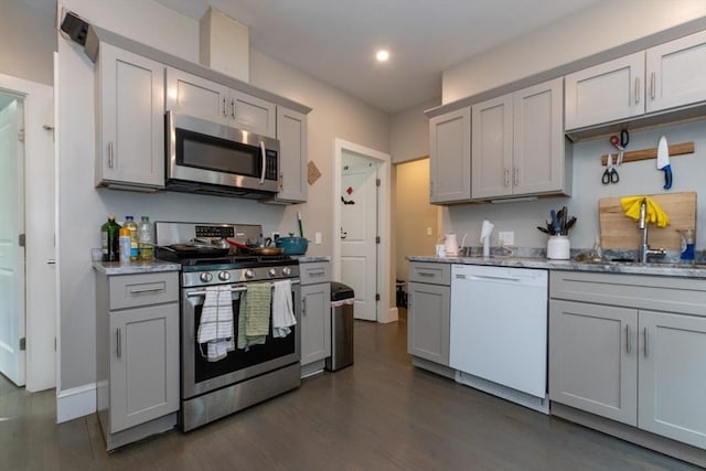 kitchen featuring appliances with stainless steel finishes, a sink, gray cabinets, dark wood-style floors, and recessed lighting