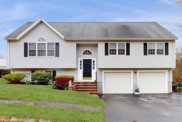 bi-level home featuring an attached garage, driveway, and a front yard