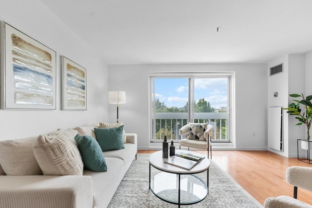 living room with visible vents, baseboards, and wood finished floors