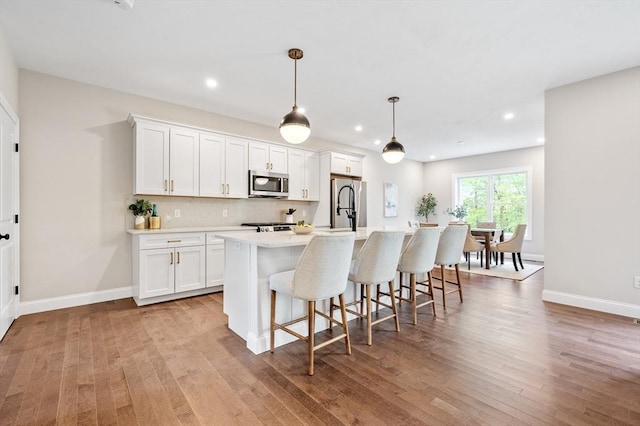59A Mount Ave, Worcester, MA 01606 - kitchen featuring stainless steel appliances, a center island with sink, light countertops, light wood-style floors, and white cabinetry