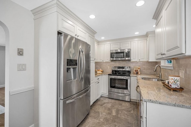 15 Eustis Ave, Wakefield, MA 01880 - kitchen featuring stainless steel appliances, a sink, arched walkways, tasteful backsplash, and white cabinetry