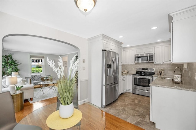 15 Eustis Ave, Wakefield, MA 01880 - kitchen with stainless steel appliances, a sink, white cabinetry, arched walkways, and tasteful backsplash