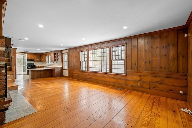 unfurnished living room with light wood-type flooring and wood walls