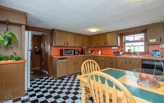 30 Everett St, Woburn, MA 01801 - kitchen featuring tile patterned floors, dishwashing machine, a sink, light countertops, and brown cabinets
