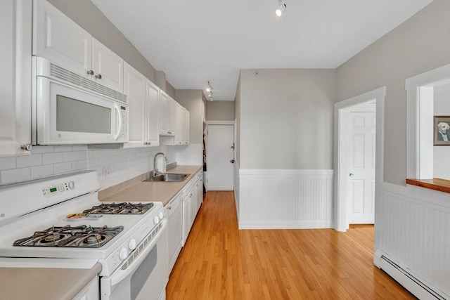 kitchen with baseboard heating, a sink, white cabinets, white appliances, and light wood-style flooring