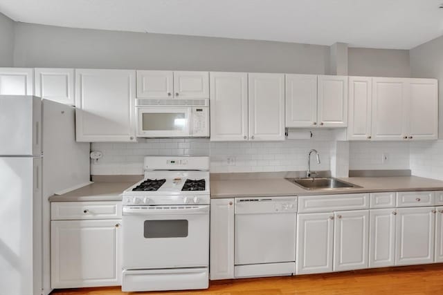 kitchen featuring white appliances, white cabinetry, and a sink