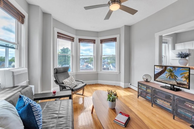 living room with baseboards, a baseboard radiator, a ceiling fan, and light wood finished floors