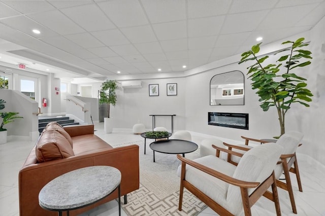 living room featuring a paneled ceiling and an AC wall unit