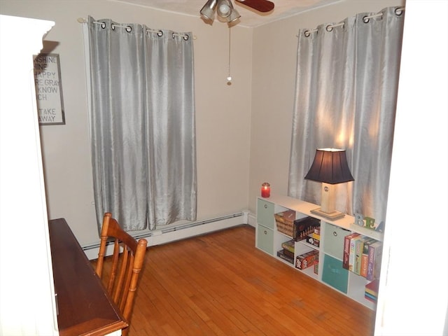 interior space with wood-type flooring, baseboard heating, and ceiling fan