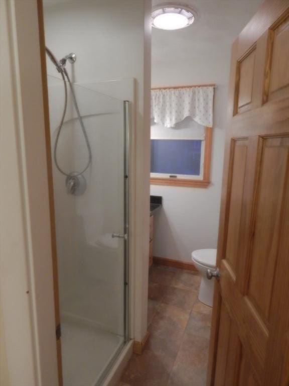 full bathroom with a shower stall, toilet, and baseboards