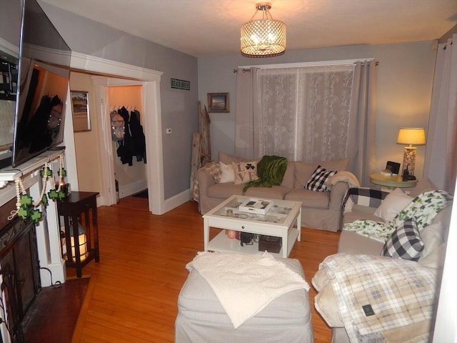 living area with a notable chandelier, baseboards, and light wood-style floors