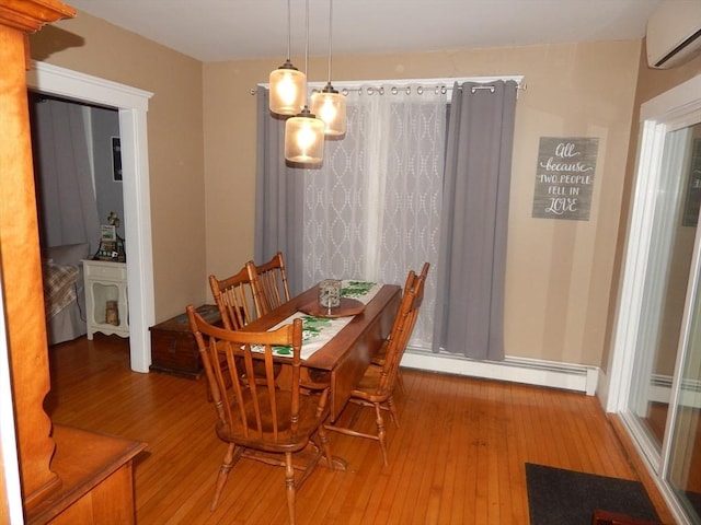 dining area featuring baseboard heating, a wall mounted air conditioner, and wood finished floors