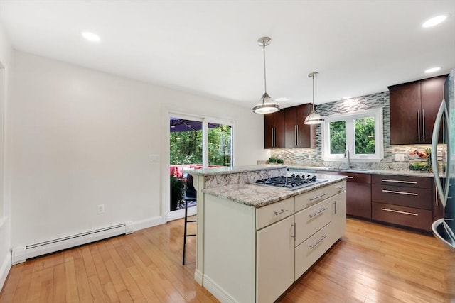 24 Azalea Way, Belchertown, MA 01007 - kitchen with a baseboard heating unit, a kitchen breakfast bar, decorative backsplash, dark brown cabinetry, and light wood-style floors