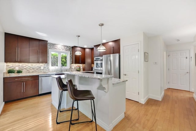 24 Azalea Way, Belchertown, MA 01007 - kitchen featuring stainless steel appliances, backsplash, a kitchen island, dark brown cabinets, and light wood-style floors