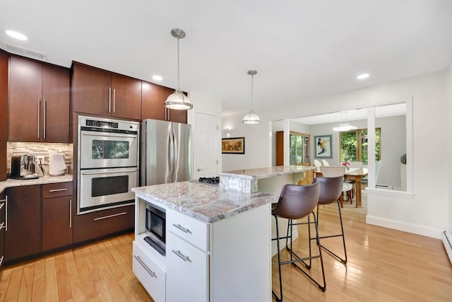 24 Azalea Way, Belchertown, MA 01007 - kitchen with stainless steel appliances, light wood-style floors, a kitchen breakfast bar, pendant lighting, and recessed lighting