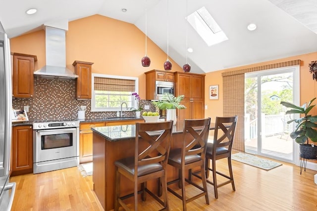 kitchen featuring appliances with stainless steel finishes, extractor fan, a skylight, brown cabinetry, and a sink