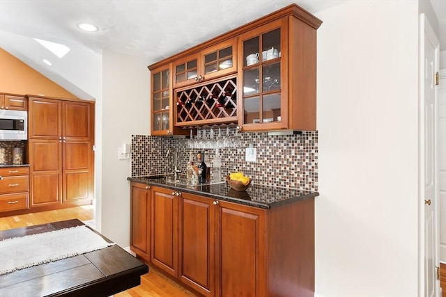 indoor wet bar featuring decorative backsplash, light wood-style flooring, and recessed lighting
