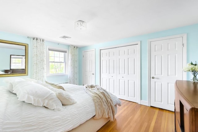 bedroom with multiple closets and light wood-style floors