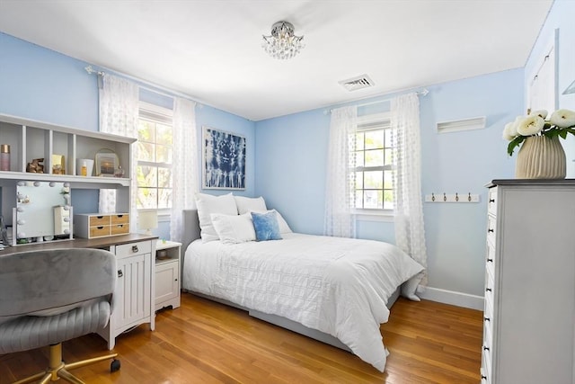 bedroom with multiple windows, light wood-type flooring, and baseboards