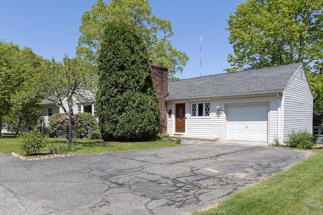 view of front of property with a chimney, an attached garage, driveway, and a shingled roof