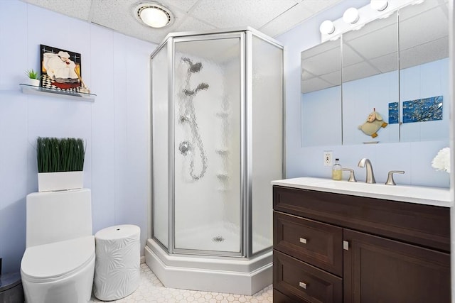 bathroom featuring a shower stall, a drop ceiling, vanity, and toilet