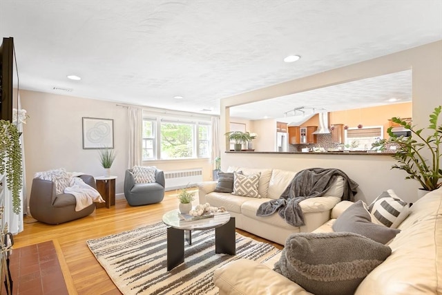 living area with radiator heating unit and wood finished floors